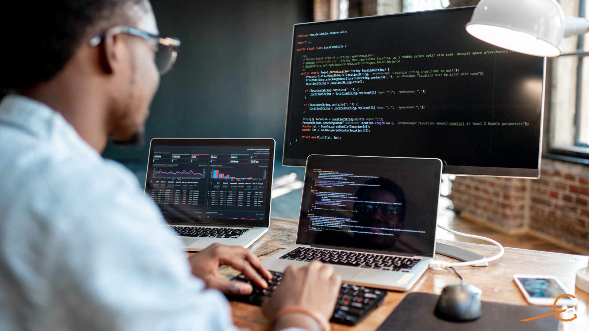 An engineer reviewing code across two laptops and a monitor